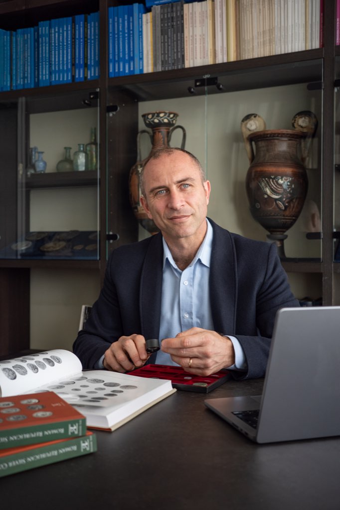 Lorenzo Moretti examining coins in his study